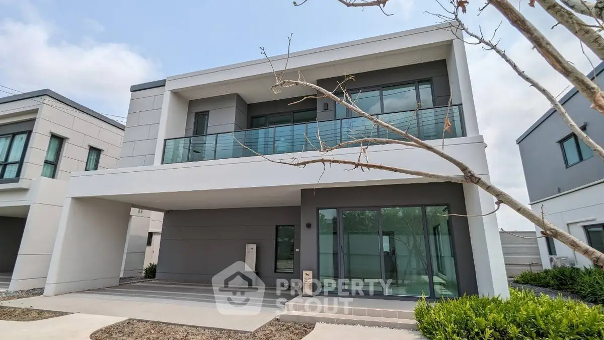 Modern two-story house with large windows and spacious balcony in a serene neighborhood.