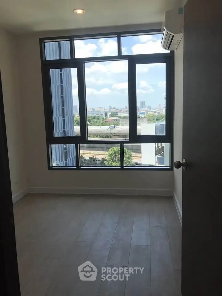 Bright bedroom with large window offering city views and modern air conditioning unit.