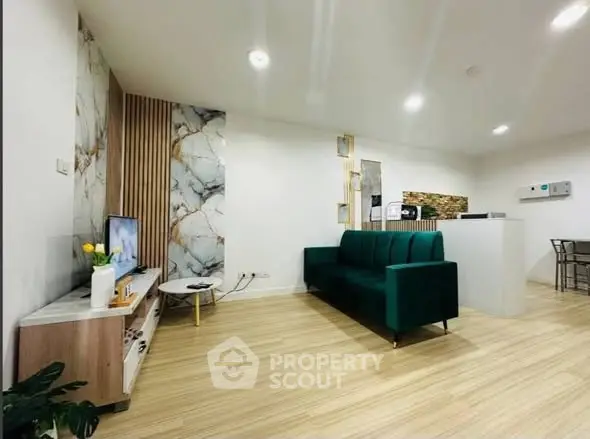 Modern living room with stylish decor and open layout, featuring a green sofa and marble accents.