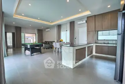 Spacious modern living room with open kitchen and pool table, perfect for entertainment.