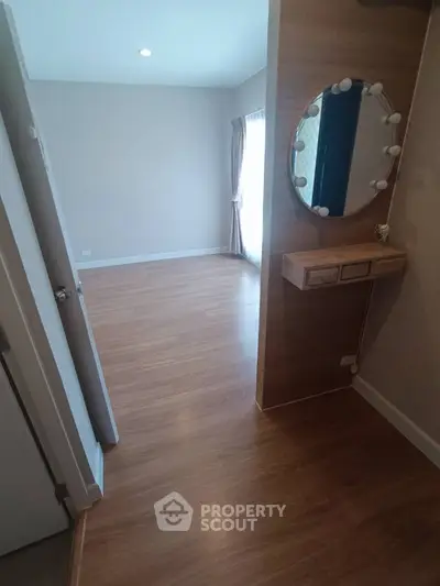 Spacious bedroom with elegant wooden flooring and stylish vanity mirror