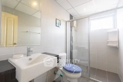 Modern bathroom with sleek design, featuring a glass shower enclosure and contemporary fixtures.