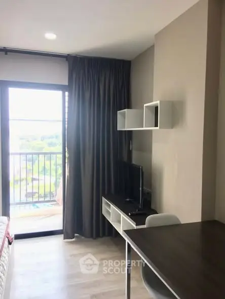 Modern study area with desk and TV in a bright apartment with balcony view.