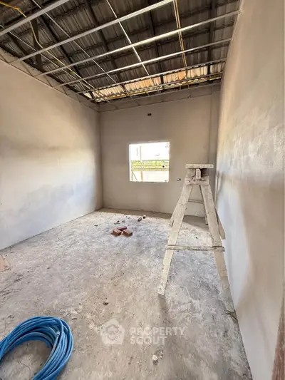 Under-construction room with unfinished walls and ceiling, featuring a ladder and construction materials.