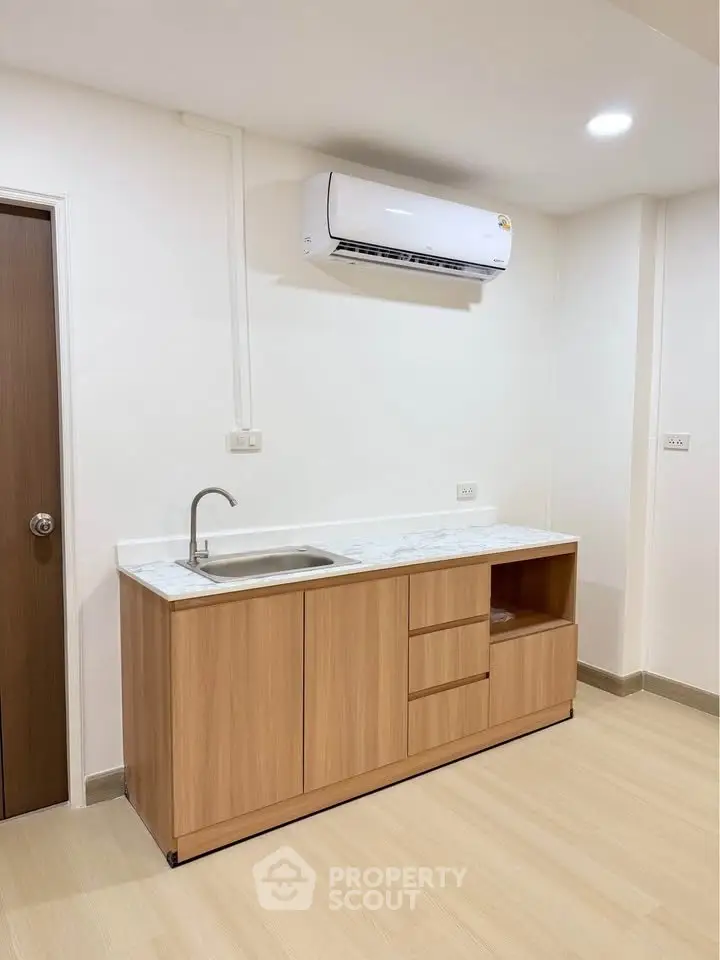 Modern minimalist kitchen with sleek cabinetry and air conditioning unit.