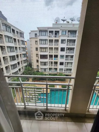 Spacious balcony view overlooking modern apartment complex with pool and lush greenery.