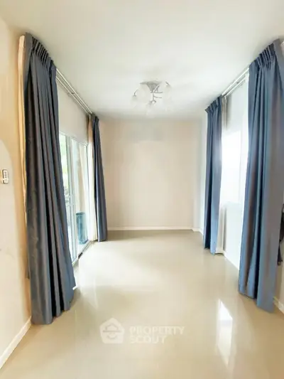 Spacious empty room with large windows and elegant curtains, perfect for customization.
