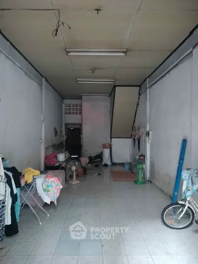 Spacious interior with high ceiling and tiled floor, ideal for storage or creative workspace.