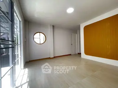 Bright and spacious living room with unique circular window and modern design.