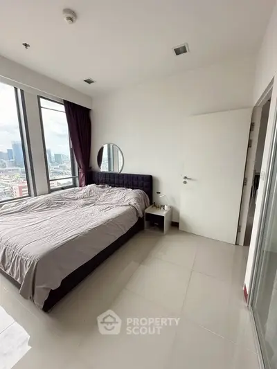 Spacious bedroom with city view and modern decor in high-rise apartment.