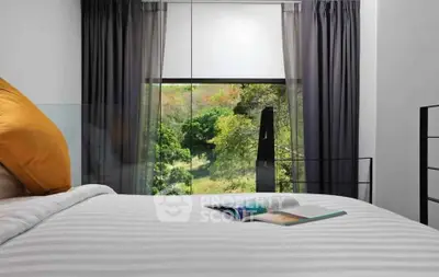 Cozy bedroom with scenic view through large window, featuring elegant curtains and a comfortable bed.