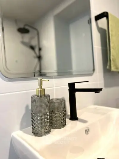 Modern bathroom sink with stylish faucet and mirror, featuring elegant soap dispenser.