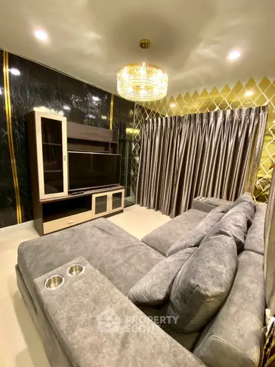 Luxurious living room with plush gray sofa, elegant chandelier, and modern entertainment center.