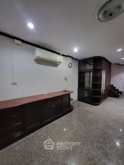 Spacious living area with built-in wooden shelves and air conditioning, ideal for modern living.
