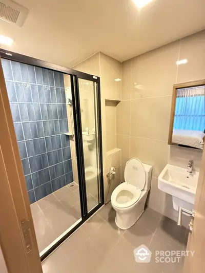 Modern bathroom with glass shower and sleek fixtures in contemporary apartment.