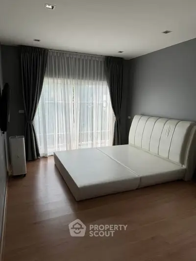 Spacious bedroom with modern minimalist design and large window for natural light.