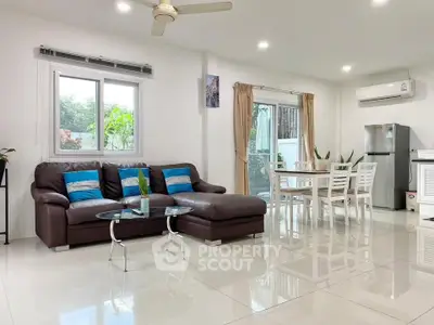 Spacious modern living room with open layout, featuring a cozy sofa, dining area, and sleek kitchen appliances.