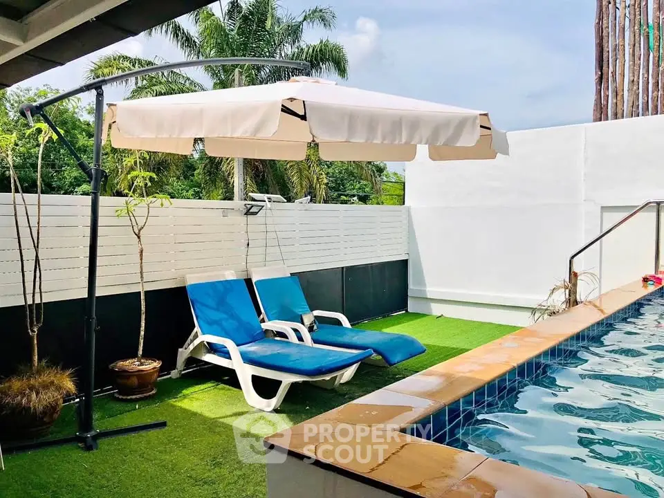 Charming poolside area with sun loungers and umbrella, perfect for relaxation.