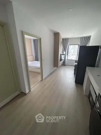 Modern apartment interior with open layout and city view, featuring a cozy bedroom and sleek kitchen.