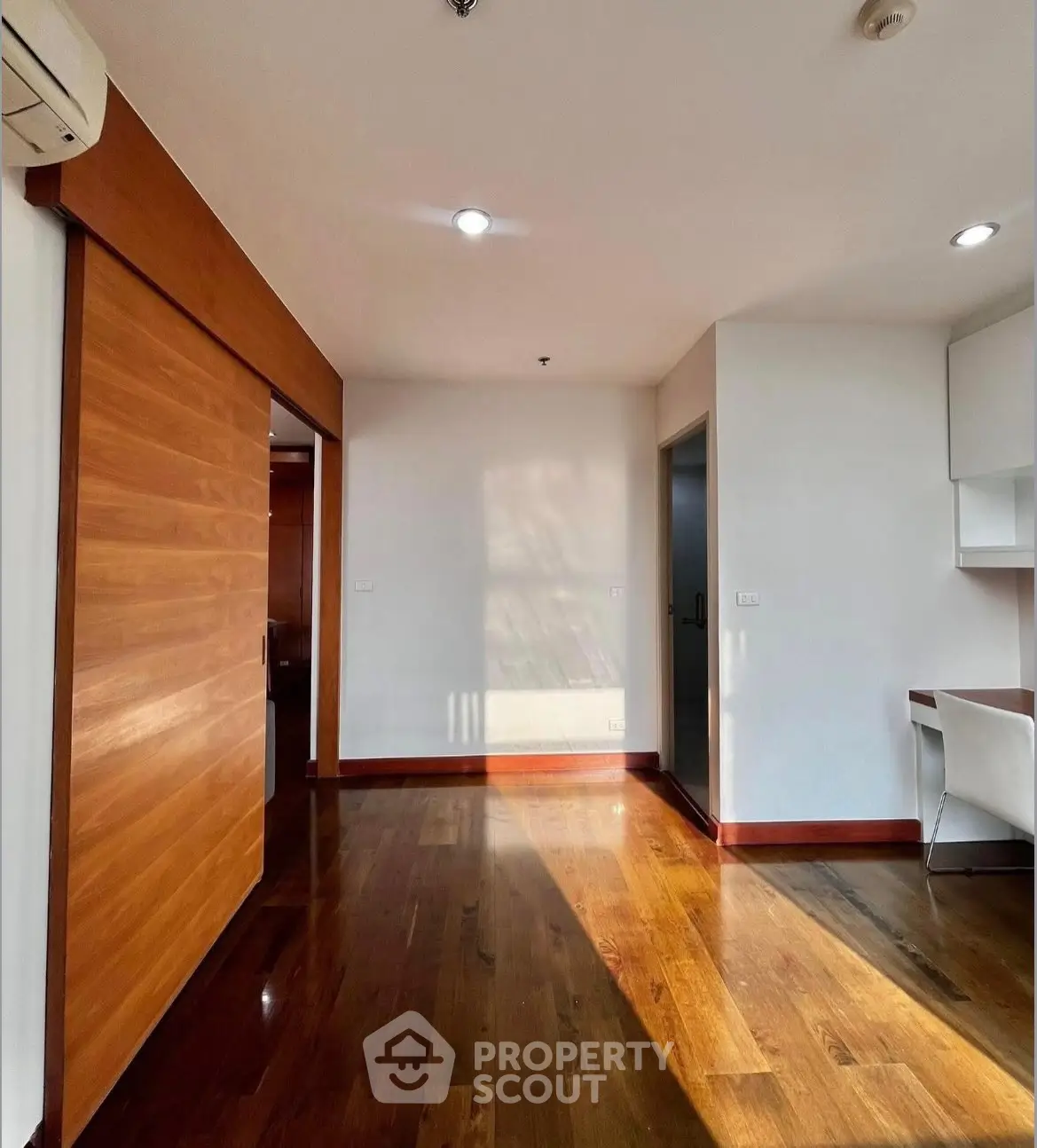 Spacious modern living room with wooden flooring and sliding door, perfect for stylish living.