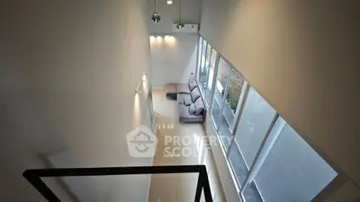 Modern loft-style living room with high ceilings and large windows.