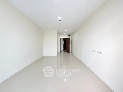 Spacious empty room with glossy tiled flooring and neutral walls, ideal for customization.