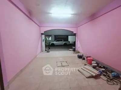 Spacious garage with pink walls and tiled floor, ideal for parking or storage.