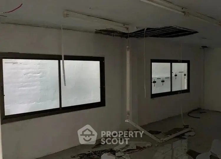 Spacious room with large windows and potential for renovation