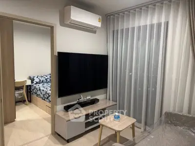 Modern living room with sleek furniture and large TV, adjacent to a cozy bedroom, ideal for urban living.
