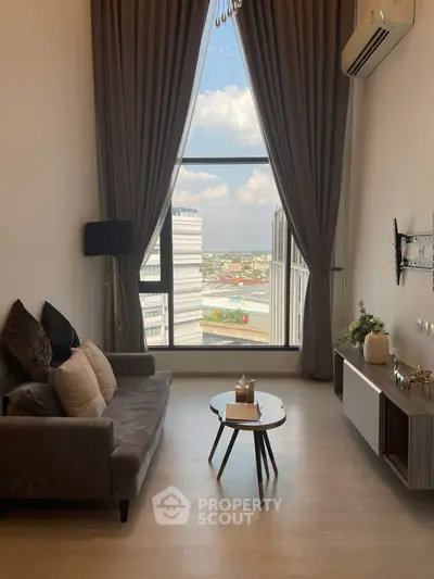 Modern living room with floor-to-ceiling window offering stunning city view, elegant decor, and cozy seating area.