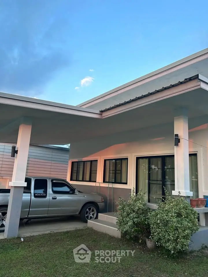 Modern single-story house with carport and lush greenery