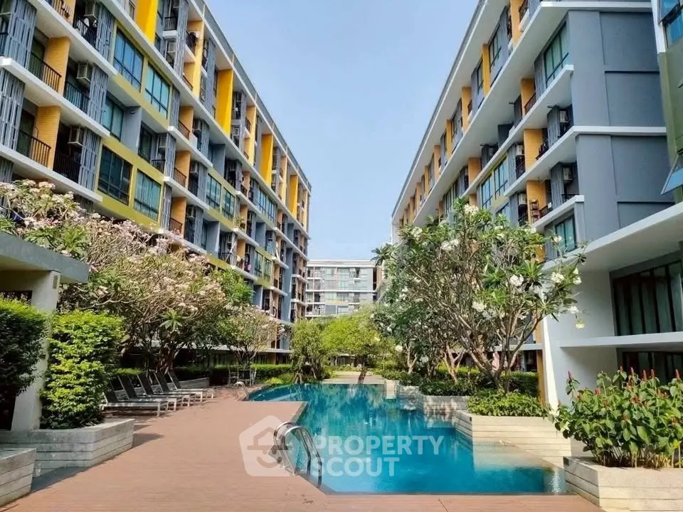 Modern apartment complex with a central swimming pool and lush greenery, offering a serene living environment.
