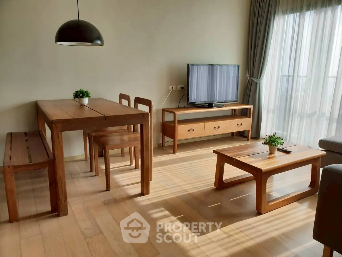 Bright living room with wooden furniture and large window, perfect for cozy gatherings.