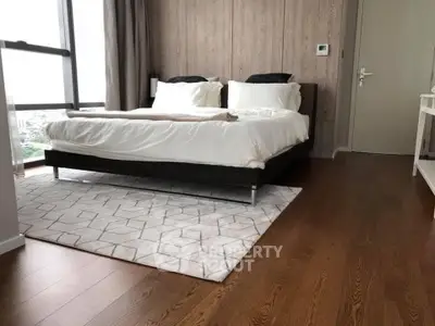 Modern bedroom with wooden flooring and large window offering city views.