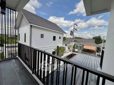 Modern balcony with sleek railing offering a scenic view of suburban houses under a clear blue sky.