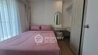 Cozy bedroom with pink bedding, wooden floor, and natural light from large window.