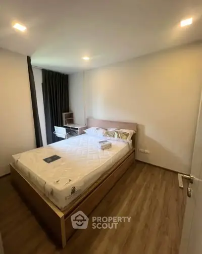 Cozy bedroom with wooden flooring and modern furnishings in a stylish apartment.