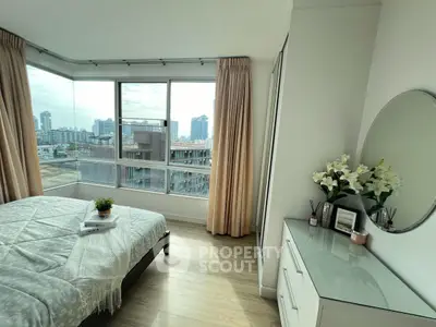 Bright bedroom with city view, featuring large windows and elegant decor.