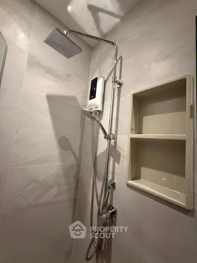 Modern bathroom with sleek showerhead and built-in shelving, perfect for contemporary living.