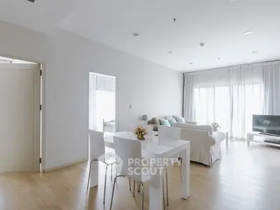 Modern living room with natural light, white furniture, and wooden flooring.