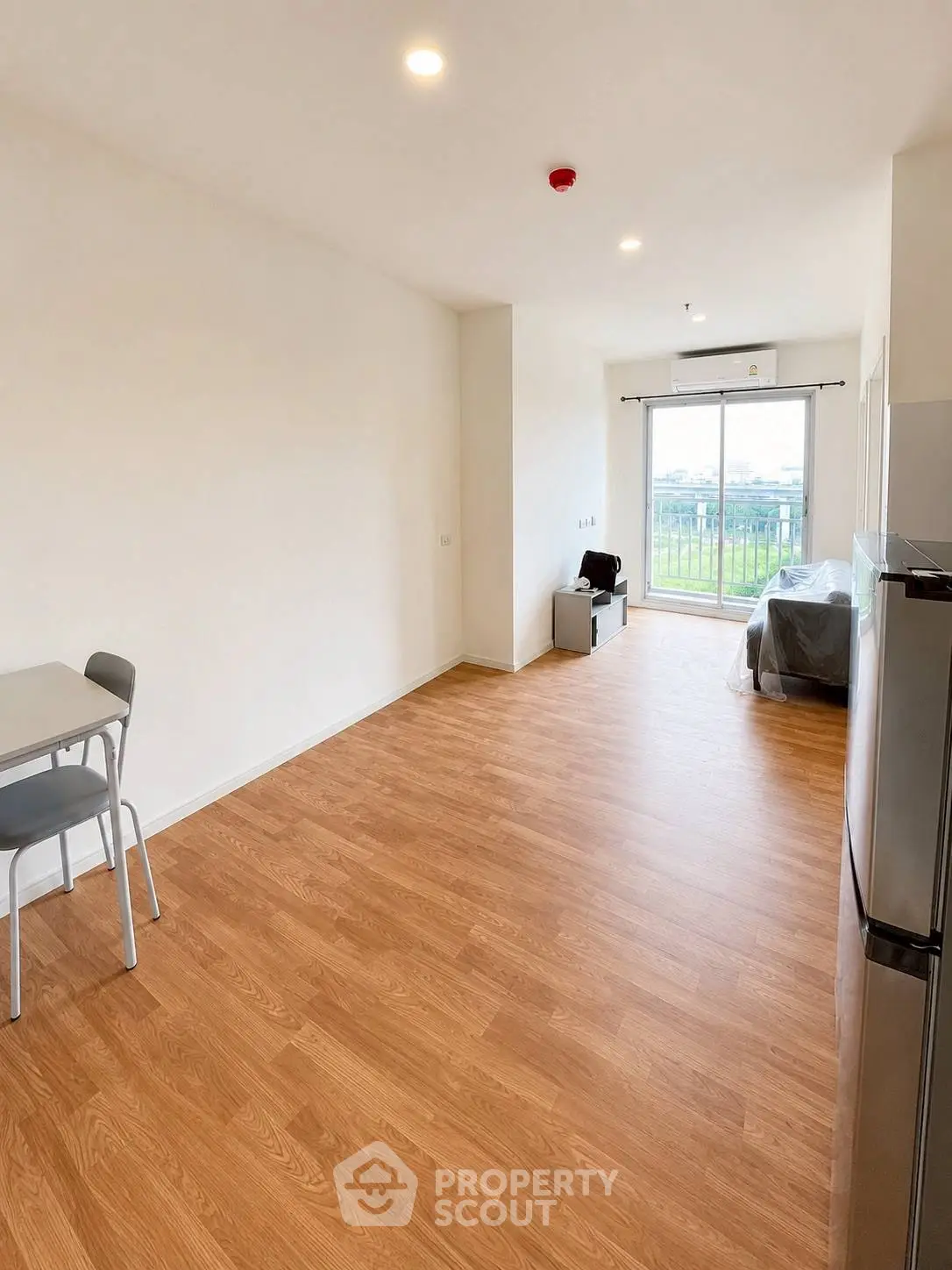 Spacious modern living room with wooden flooring and large window view.