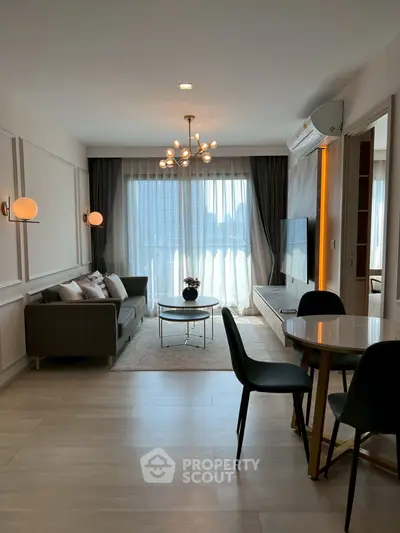 Modern living room with stylish decor and large window offering city view.