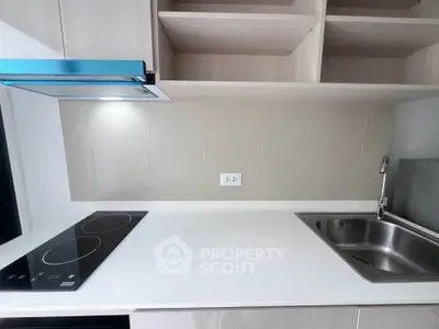 Modern kitchen with sleek electric cooktop and stainless steel sink, ideal for contemporary living.