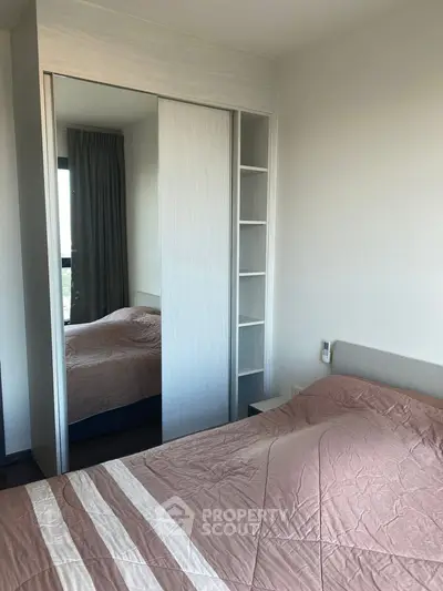 Modern bedroom with mirrored wardrobe and cozy bedding in a stylish apartment.