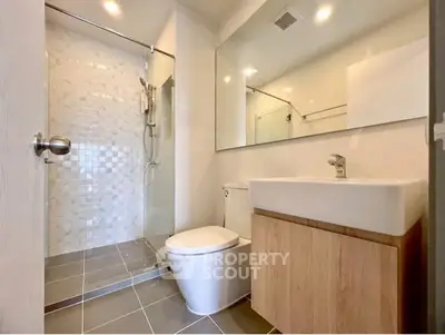 Modern bathroom with sleek fixtures and spacious shower in contemporary apartment.