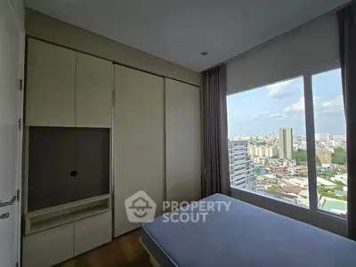 Modern bedroom with large window offering stunning city view and built-in wardrobe.
