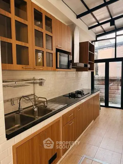 Modern kitchen with wooden cabinets, gas stove, and ample natural light