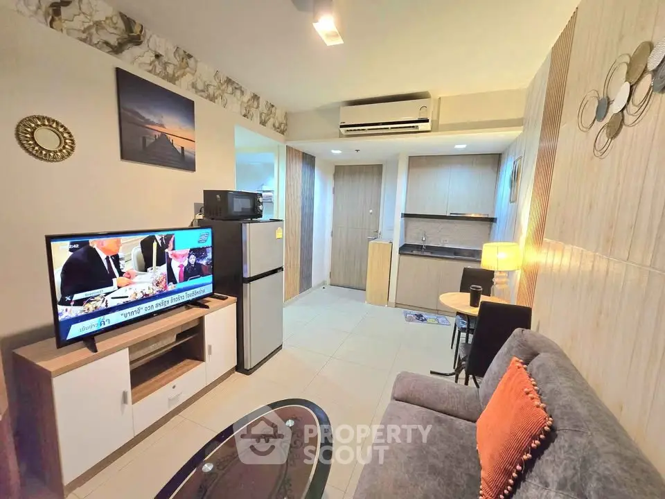 Modern living room with kitchenette, featuring cozy sofa and wall-mounted TV for a comfortable lifestyle.