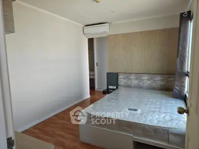 Modern bedroom with wooden flooring and natural light, featuring a comfortable bed and air conditioning.