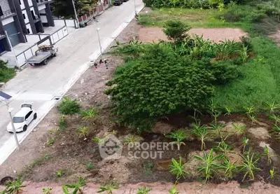 Aerial view of a residential plot with lush greenery and developing infrastructure.
